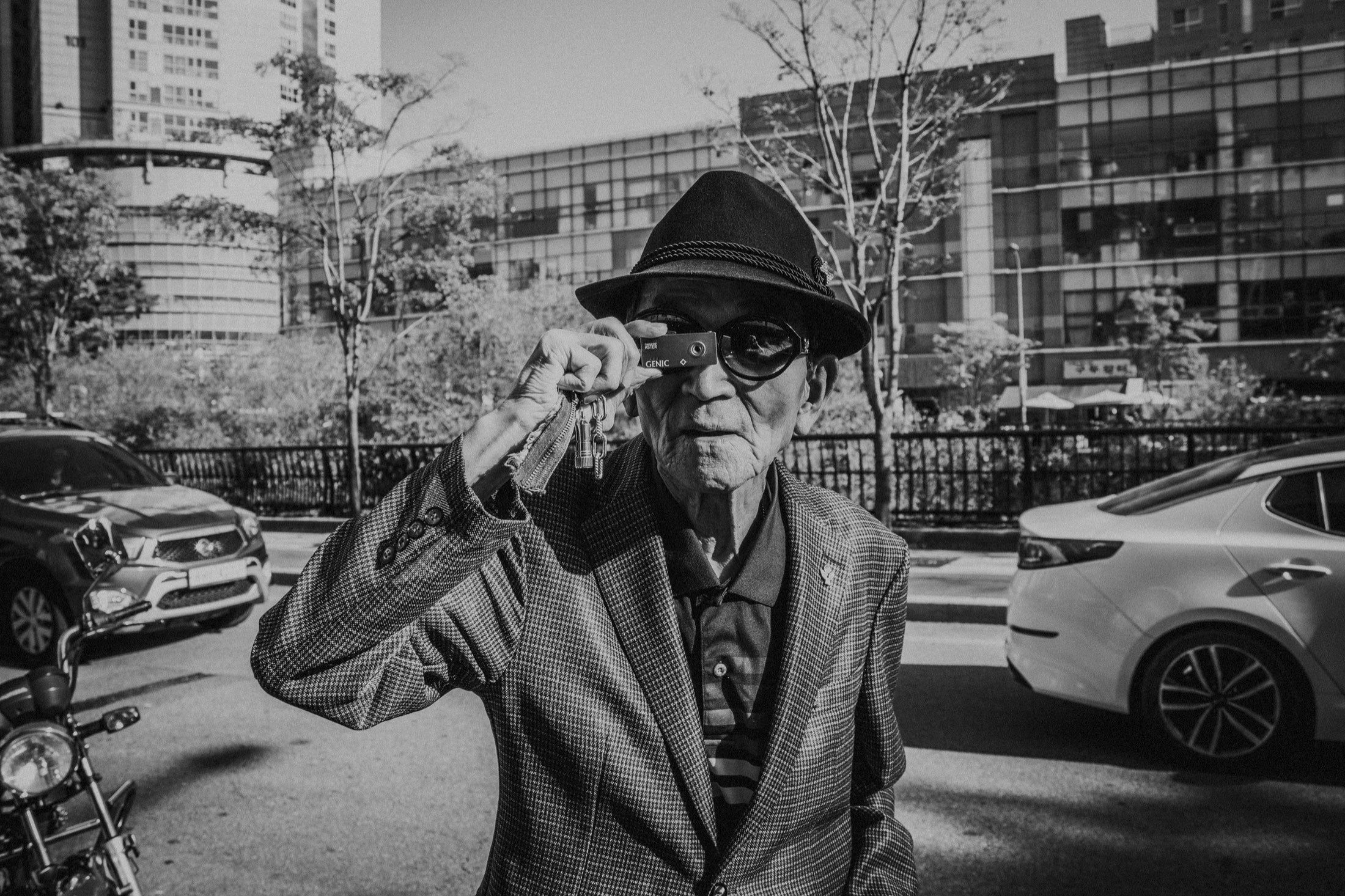 Dongmyo, Seoul: a man in a hat holds ASTER, the GENIC metal keychain camera, to his eye